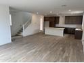 A light-filled room with wood floors, a kitchen with an island, and a white staircase at 2455 W Rowel Rd, Phoenix, AZ 85085
