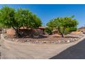 Landscaped front yard featuring desert landscaping with mature trees adding curb appeal to this charming single-story home at 1448 E Royal Palm Rd, Phoenix, AZ 85020