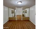 Bright bedroom with laminate floors, two mirrored closets, and storage at 303 S Recker Rd # 74, Mesa, AZ 85206
