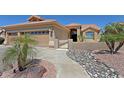 Charming home with a three-car garage, desert landscaping, and a walkway to the front door at 3147 N Couples Dr, Goodyear, AZ 85395