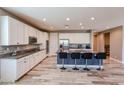 Modern kitchen with white cabinetry, granite counters, stainless appliances, large island with seating, and wood floors at 3907 S 75Th Dr, Phoenix, AZ 85043