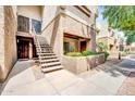 A two-story home with tan stucco walls and a stairway leading up to the front door, surrounded by landscaping at 4554 E Paradise Village Pkwy # 161, Phoenix, AZ 85032