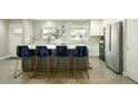 Stylish kitchen with a central island, white cabinets, stainless steel refrigerator and four comfortable bar stools at 8115 E Cypress St, Scottsdale, AZ 85257