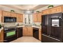 Bright kitchen with granite countertops, black appliances, custom cabinetry, and a window overlooking a landscaped yard at 8785 E Sandtrap Ct, Gold Canyon, AZ 85118
