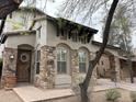 Charming front exterior features a stone facade, dark wood accents, and an arched entryway, framed by desert landscaping at 9285 E Canyon Vw, Scottsdale, AZ 85255