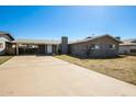 Single-story house exterior with long driveway, chimney, carport, and desert landscaping at 1055 W Dragoon Ave, Mesa, AZ 85210