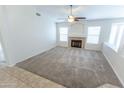 Spacious living room featuring a cozy fireplace, large windows, and plush carpeting at 1366 E Desert Fern Trl, Casa Grande, AZ 85122