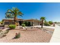 Attractive home featuring desert landscaping including gravel, rocks and mature palm trees at 15136 W Cactus Ridge Way, Surprise, AZ 85374