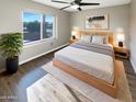 Cozy bedroom showcasing a bed, ceiling fan, wood floors, and lots of natural light at 3134 E Mckellips Rd # 50, Mesa, AZ 85213