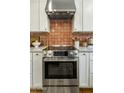 Close-up of a stainless steel stove and hood with decorative red tile backsplash in updated kitchen at 8361 E Via De Viva --, Scottsdale, AZ 85258
