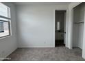 A bright bedroom with neutral carpet, a window with blinds, closet, and an attached bathroom at 15786 W Cheryl Dr, Waddell, AZ 85355