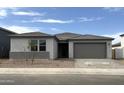 A charming single-story home featuring a gray color palette, attached two-car garage, and gravel landscaping at 15786 W Cheryl Dr, Waddell, AZ 85355