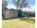 Well-maintained single-story home boasting a lush front lawn, mature trees, and stone accents at 1257 E Dartmouth St, Mesa, AZ 85203