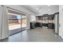 Open kitchen featuring dark cabinetry, modern appliances, and a seamless transition to outdoor space at 14521 W Gelding Dr, Surprise, AZ 85379