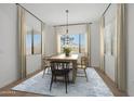 Bright dining room with a wooden table, modern chandelier, large windows, and a stylish blue area rug at 20373 W Rovey Ave, Buckeye, AZ 85396
