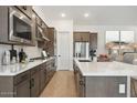 Modern kitchen featuring stainless steel appliances, white countertops, wood flooring, and sleek, dark wood cabinetry at 20373 W Rovey Ave, Buckeye, AZ 85396