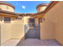 Private courtyard featuring a wrought iron gate, neutral stucco, and brick pavers under a bright blue sky at 2041 N 88Th St, Mesa, AZ 85207