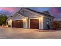 A spacious three-car garage featuring beautiful doors, exterior lighting, and a well-maintained driveway at 23040 W Hammond Ln, Buckeye, AZ 85326