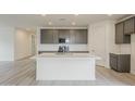Modern kitchen featuring a large island with white quartz countertops, grey cabinets, and stainless steel appliances at 40030 W Bunker Dr, Maricopa, AZ 85138