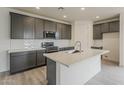 Spacious kitchen with grey cabinets, quartz countertops, stainless steel appliances, and large kitchen island at 40030 W Bunker Dr, Maricopa, AZ 85138