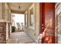 Covered front porch featuring stone columns, decorative lighting, and a solid wood entry door at 4252 E Vest Ave, Gilbert, AZ 85295