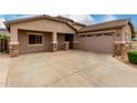 Attached garage with multi-car driveway featuring stone accents and desert landscaping at 4255 S Marisol Ln, Gilbert, AZ 85297