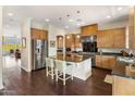 Open kitchen featuring wood cabinets, stainless steel appliances, island with bar seating, and dark wood floors at 7275 N Scottsdale Rd # 1001, Paradise Valley, AZ 85253