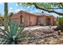 Charming home exterior with desert landscaping, mature trees, and a quaint courtyard entrance at 11451 E Christmas Cholla Dr, Scottsdale, AZ 85255