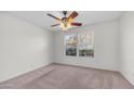 Cozy bedroom with soft carpet, ceiling fan, and bright windows with views of greenery at 15825 W Acapulco Ln, Surprise, AZ 85379