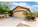 Lovely home featuring a two-car garage and desert landscaping with rocks and palm trees at 4140 E Sundance Ave, Gilbert, AZ 85297
