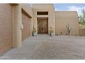 Stunning front entrance featuring custom wood doors, lush plantings, and a circular driveway at 8625 E Camino Vivaz --, Scottsdale, AZ 85255