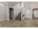 Welcoming foyer with staircase, tile flooring, and elegant light fixture at 17370 W Pima St, Goodyear, AZ 85338