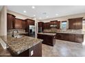 Spacious kitchen featuring granite countertops, dark wood cabinetry, stainless steel appliances, and a functional kitchen island at 21525 E Camacho Rd, Queen Creek, AZ 85142