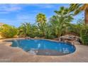 Tropical backyard oasis with a lagoon-style pool, waterfall, and lush landscaping at 21525 E Camacho Rd, Queen Creek, AZ 85142