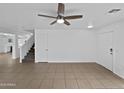 Spacious living room featuring tile flooring, a ceiling fan, and easy access to the stairs and kitchen at 217 E Gwen St, Phoenix, AZ 85042