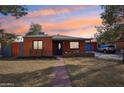 Charming red brick home featuring a well-maintained lawn and an inviting walkway during a colorful sunset at 2511 E Pinchot Ave, Phoenix, AZ 85016