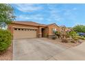 Tan home with desert landscaping, tile roof, and large driveway at 37161 W Giallo Ln, Maricopa, AZ 85138