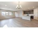 Open-concept living area with wood floors, recessed lighting, and a modern chandelier at 39960 W Bunker Dr, Maricopa, AZ 85138
