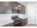 Modern kitchen features gray cabinets, stainless steel appliances, white backsplash, and sleek countertops at 40025 W Bunker Dr, Maricopa, AZ 85138