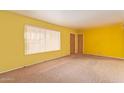 Bright living room with yellow walls, neutral carpeting, and natural light streaming through the window at 5445 E Dallas St, Mesa, AZ 85205