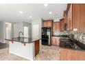 Open kitchen with black appliances, wood cabinets, granite counters, tile backsplash, and a center island with a breakfast bar at 7622 S 69Th Dr, Laveen, AZ 85339