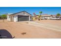 Single-story home with a gray garage door, desert landscaping, and a spacious driveway for easy parking at 1012 E Estevan Ave, Apache Junction, AZ 85119