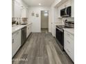 Modern kitchen featuring stainless appliances, white cabinets, and hardwood flooring at 10927 W Peoria Ave, Sun City, AZ 85351