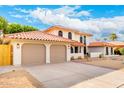Two-car garage with extended driveway and red tile roof, desert landscaping in front yard at 17012 N 57Th St, Scottsdale, AZ 85254