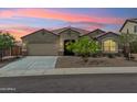 Charming single-story home featuring a well-manicured front yard and attached two-car garage during sunset at 31096 N 133Rd Ave, Peoria, AZ 85383