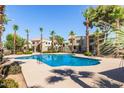 Inviting community pool surrounded by lush landscaping and palm trees under a clear blue sky at 4828 W Rancho Dr, Glendale, AZ 85301