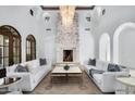 Elegant living room featuring a stone fireplace, chandeliers, and white sofas in a bright, open space at 8601 N 59Th Pl, Paradise Valley, AZ 85253