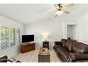 Bright living room features tile flooring, shutters, and a comfortable leather sofa at 11925 N 67Th Dr, Peoria, AZ 85345