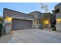 Attached two-car garage and wide driveway, complemented by the home's stucco exterior and warm exterior lighting at 19475 N Grayhawk Dr # 1046, Scottsdale, AZ 85255