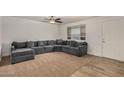 Spacious living room with a cozy gray sectional couch, ceiling fan, and natural light at 299 N Comanche Dr, Chandler, AZ 85224
